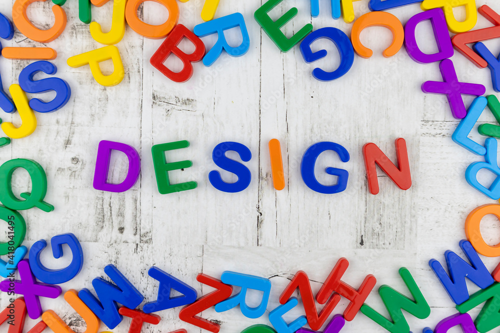 Fototapete word - design - in multicolored alphabet letters centered with frame on a grey wood background viewe