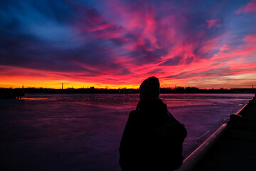 Amazing red sunrise sky with clouds over black silhouette of girl. Selective focus