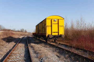 Fototapeta na wymiar Abandoned yellow train wagon, weathered and rusty, on an old train tracks