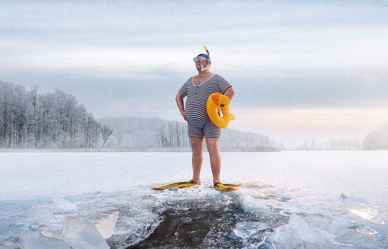 Fuunny overweight, retro swimmer standing by the ice hole in the lake, at the cold sunrise with copy space