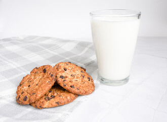 A beautiful morning with a healthy and hearty breakfast, a glass of fresh milk and a few pieces of oatmeal cookies with pieces of chocolate, white background. The concept of proper nutrition