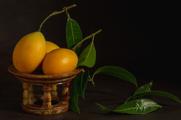 Marian plum fruits on little kantoke isolated on dark background.