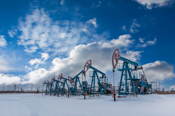 Several Oil pumpjack under the blue sky with clouds winter working. Oil rig energy industrial machine for petroleum in the sunset background for design.