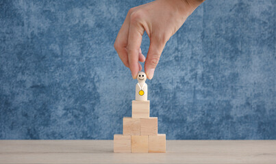 wood doll with gold medal on top of wooden cube stack with winner word, successful concept
