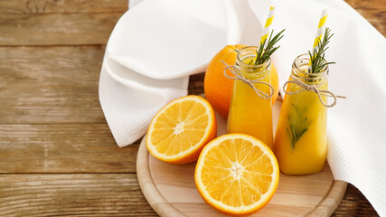 Orange juice in glass bottles. The juice is decorated with a sprig of rosemary