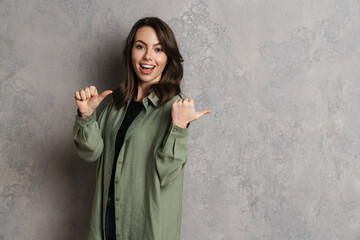 Happy beautiful brunette girl smiling and pointing fingers aside