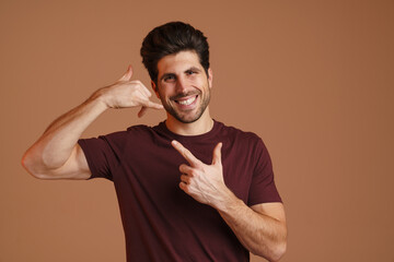 Happy man pointing finger upward while showing handset gesture