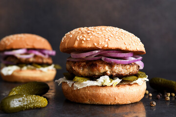 Homemade grilled burger with beef, cucumber, salad and onions. With copy space.