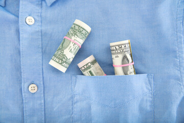 There are dollar bills in the pocket of the blue shirt