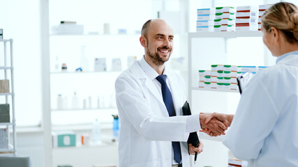 Naklejka na ściany i meble senior pharmacist shaking hands with his assistant.