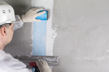 a worker reinforces the concrete wall with a special blue mesh