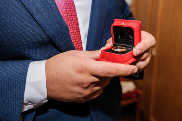 Wedding gold rings in a red box, wedding gold rings in the hands of the groom