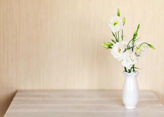 White flowers Eustoma or Lisianthus in vase on wooden background with copy space