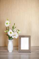 Mockup with photoframe, White flowers Eustoma or Lisianthus in vase on wooden background with copy space