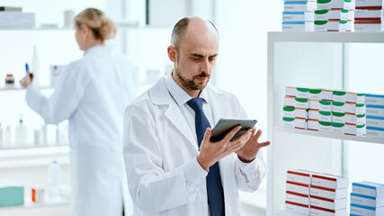 Naklejka na ściany i meble pharmacist with a digital tablet standing near a display case with medicines.