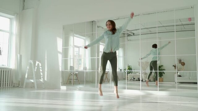 Happy young woman jumping in the room, celebrating success