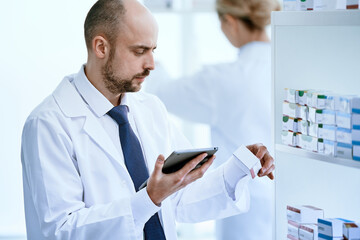 pharmacist with a digital tablet looking at a box of medicines.