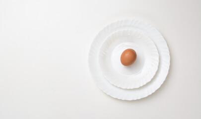 Three white plates of different sizes on top of each other. The last one has an egg on it. Concept - healthy food, diet.