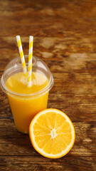 Orange juice in fast food closed cup with tubes on wooden table. Fresh summer drink. Photo for banner or advertisement of cafe and menu