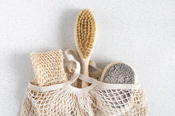 natural bathroom accessories, washcloth, wooden anti-cellulite body brush, dry massage, loofah, bodycare on cloth shopping string bag, light background. zero waste, eco-friendly home