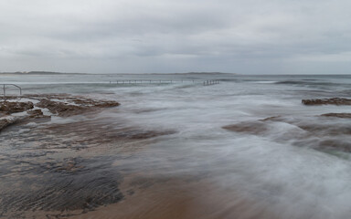 Fototapeta na wymiar Wave water flowing between rocks on the coastline.