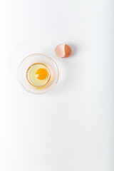 Bright yellow egg yolks in a glass  bowl with  eggshell on white background