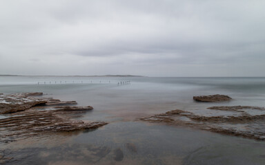 Fototapeta na wymiar Rocky coastline and tidal pool view on a cloudy day.