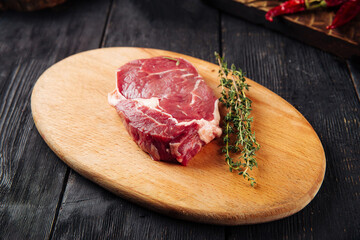 Side view on raw piece of meat with rosemary on the wooden board