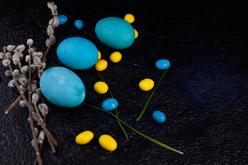 Fototapeta na wymiar Multicolored easter eggs and pussy willow branches on dark textured background