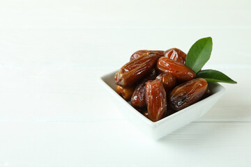 Bowl with dried dates on white wooden table