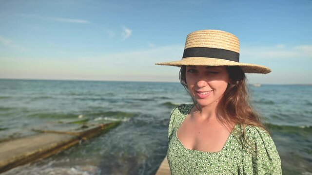 Portrait of a young caucasian beauty woman with the ocean in the background. Beautiful fashionable woman looking at the camera and smiling cheerfully in slow motion