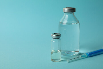 Vials with Covid - 19 vaccine and syringe on blue background