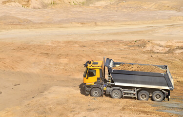 Dump truck transports sand in open pit mine. In the production of concrete, concrete for the construction using coarse sand. Quarry in which sand and gravel is excavated from ground. Mining industry