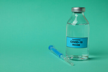 Vial of Covid - 19 vaccine and syringe on mint background