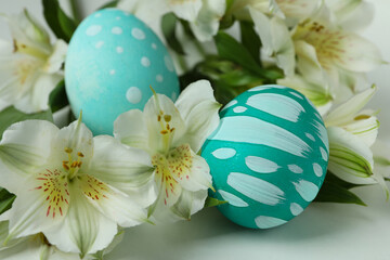 Color Easter eggs and alstroemeria flowers on white background, close up