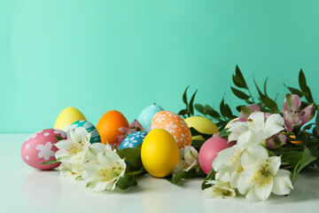 Color Easter eggs and alstroemeria flowers against mint background