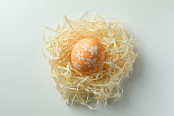Beautiful orange Easter egg in nest on white background