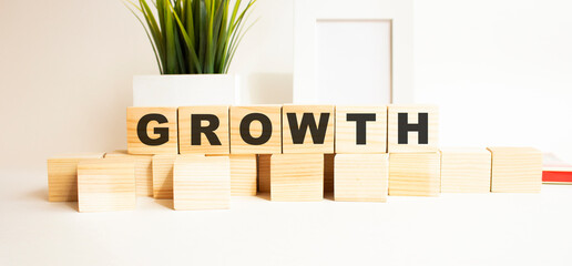 Wooden cubes with letters on a white table. The word is GROWTH. White background.