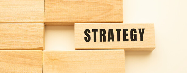 STRATEGY text on a strip of wood lying on a white table.