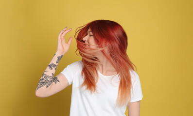 Young woman with bright dyed hair on yellow background