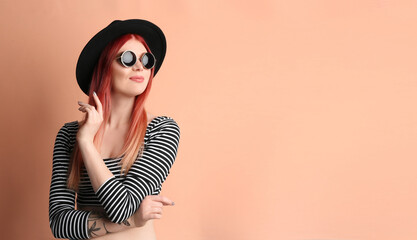 Young woman with bright dyed hair on pale pink background