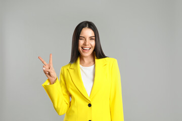 Woman showing number two with her hand on grey background
