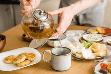 A man pours black tea into a ceramic mug