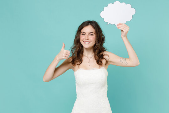 Smiling bride young woman 20s in white wedding dress hold empty blank Say cloud, speech bubble showing thumb up like isolated on blue turquoise background studio. Ceremony celebration party concept. - Powered by Adobe