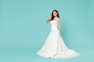 Full length of smiling tender bride young woman in white wedding dress showing thumb up like...