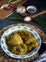 Ayam ungkep bumbu kuning or marinated chicken. Cooked with herbs spices such as turmeric, lemon grass, garlic, coriander, ginger, lime leaves, candle nuts. Ready to be fried. Ingredients in frame.