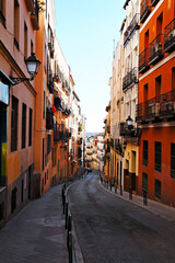 Fototapeta premium Narrow street between bright red and orange houses in Barcelona, travel walking, sidewalk, Spain