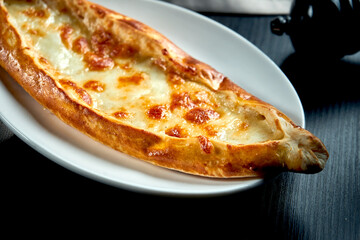 Turkish pide dish with tomatoes and salted cheese on black background