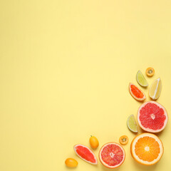 Fresh juicy citrus fruits on light yellow background, flat lay. Space for text