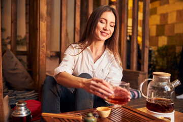 Beautiful young woman enjoying tea ceremony in cafe